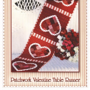 May include: Red and white patchwork heart-shaped table runner with white scalloped edges. The table runner is displayed on a white wicker chair with a bouquet of red and white flowers. The text "Patchwork Valentine Table Runner" is at the bottom of the image.