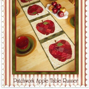 May include: A patchwork apple table runner with red and green fabric squares. The runner is laid out on a wooden table with red bowls and green plates. The text "Patchwork Apple Table Runner" is at the bottom of the image.