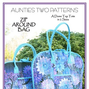 May include: Two quilted tote bags with floral patterns in shades of blue, purple, and white. The bags have rounded tops, matching handles, and exterior pockets. The text "ZIP AROUND BAG" and "A Dome Top Tote" are visible. The tall bag is 16" wide x 6" deep x 14" tall.