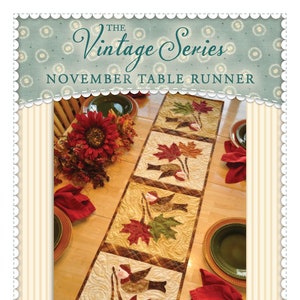 May include: The Vintage Series November Table Runner sewing pattern features a quilted table runner with a fall theme. The runner is made of fabric with a brown, green, and orange color scheme and features birds and leaves. The pattern is available from Shabby Fabrics.