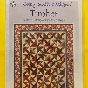 May include: Quilt pattern instructions for a "Timber" quilt. The pattern is designed for 2 1/2 inch strips and includes instructions for throw, twin, and queen size quilts. The quilt design features a geometric pattern of red, black, and white triangles.