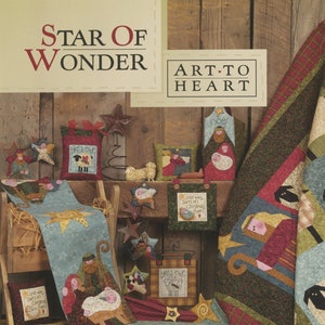 May include: A collection of Christmas-themed quilted fabric crafts, including a table runner, pillows, and wall hangings. The crafts feature a variety of designs, including stars, angels, and the nativity scene. The fabrics are in shades of red, green, blue, and brown.