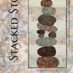 May include: A fabric art piece featuring a stack of stones in shades of brown, blue, and tan. The artwork is rectangular, with a finished size of 14 inches by 36 inches. The text "STACKED STONES" is displayed vertically.