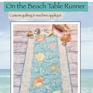 May include: A blue and white table runner with a seashell design. The runner is decorated with seashells, starfish, and a seashell border. The text "On the Beach Table Runner" and "Custom quilting & machine appliqué" is at the top of the image. The text "AMÉLIE SCOTT DESIGNS" is at the bottom of the image. A gold star with the text "Dealer Exclusive!" is in the lower right corner of the image.