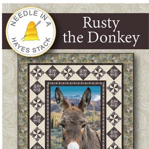 May include: A quilt kit featuring a close-up of a donkey named Rusty, set against a desert landscape. The quilt has a patterned border and measures 60" x 76". The text "Rusty the Donkey" is displayed at the top.