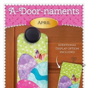 May include: A-Door-naments April door hanger with a green background and three colorful Easter eggs. The hanger is decorated with a butterfly and flowers. The text "Additional Display Option Included" is also visible.