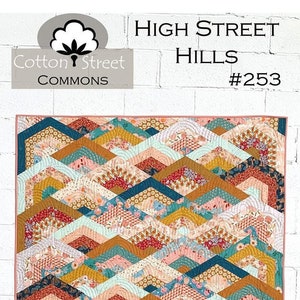 May include: A quilt pattern called "High Street Hills #253" by Cotton Street Commons. The quilt features a geometric design of overlapping hexagons and arches in shades of teal, peach, gold, and white.