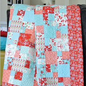 May include: A quilt pattern called "Tidbits" with the pattern number #SGD003. The quilt is made with a variety of red, white, and blue fabrics with floral and geometric patterns. The quilt is quilted with a swirling pattern. The quilt is made by Swirly Girls.