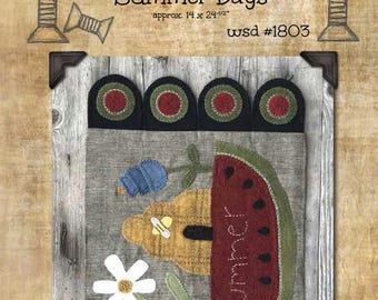 May include: A needlepoint pattern for a wall hanging featuring a watermelon, a beehive, flowers, and berries. The pattern is titled "Summer Days" and is approximately 14 by 24 and a half inches. The pattern is from Wooden Spool Designs and is number 1803.