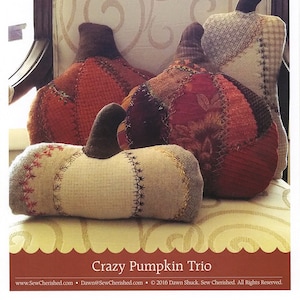 May include: A sewing pattern for a trio of patchwork pumpkins. The pumpkins are in various shades of brown, red, and white. The pattern is titled "Crazy Pumpkin Trio" and includes the website address www.SewCherished.com.