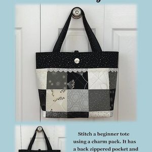 May include: A Charming Button Tote Bag, black with white polka dots, is displayed. The tote bag is 13.5 inches high, 19 inches wide, and 6 inches deep. The bag has a patchwork design in shades of gray and white, with a lace trim and a button closure.