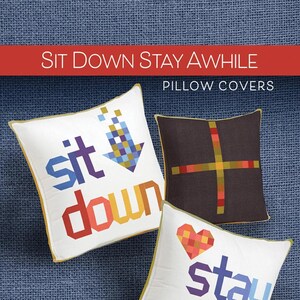 May include: Three colorful pillow covers with the text "Sit Down Stay Awhile" in a pixelated font. The pillow covers are white with a yellow border and feature different designs. The first pillow cover has the words "sit down" with a blue and yellow arrow pointing down. The second pillow cover has a brown background with a yellow and red cross. The third pillow cover has a red heart and the words "stay awhile".