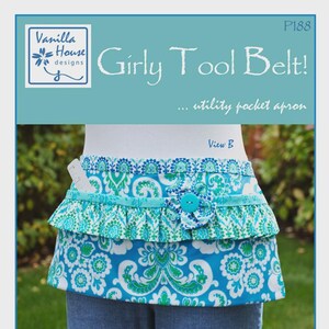 May include: A "Girly Tool Belt!" utility pocket apron with a blue and white floral pattern, turquoise ruffles, and a large button detail. The apron has a pocket and is displayed on a mannequin. The text "Ruffles made Easy!" is also visible.
