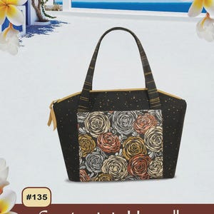 May include: Black tote bag with a floral rose pattern and gold accents. The bag has a zipper closure and a striped handle. The text "Pink Sand Beach Designs" and "Santorini Handbag" are visible.