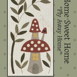 May include: A folk art design featuring a whimsical mushroom house with a red and white spotted cap, gray stem, and yellow windows. Two ladybugs perch on leafy branches. The text reads "Home Sweet Home" and "Fly Away Home". Finished size: 8" x 16".