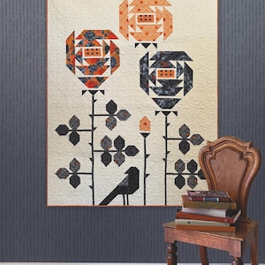 May include: A quilt titled Visitor Among the Roses featuring three stylized floral blooms in orange and dark gray patterns on a cream background, with a black bird silhouette at the base. The quilt has an orange border and is by Robin Pickens.