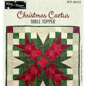 May include: A red and green Christmas Cactus table topper quilt pattern with a starburst design. The finished size is 24 inches square. The pattern is called "Christmas Cactus" and is from Wing and a Prayer Design.