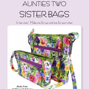 May include: Two floral patterned fabric bags with purple zippers and green trim. The larger bag has a long strap, while the smaller bag has a shorter strap. The bags are made from Hoffman CA Fabrics digital prints. The text "Aunties Two" is in the bottom left corner, along with the email address "info@auntiestwo.com", the copyright year "2018", and the pattern number "AT625".
