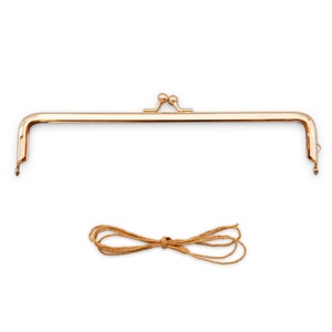 May include: A gold-colored metal purse frame with a kiss-lock clasp and a matching brown cord. The frame is rectangular with curved corners and small loops on each end for attaching to fabric. The cord is tied in a bow.