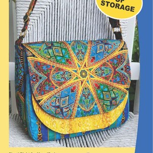 May include: A colorful, patterned shoulder bag with the text "The Flaptastic Bag" and "Oodles of Storage." The bag features a double flap front and a full-width front pocket. Dimensions are 12 inches wide, 9.5 inches tall, and 4.5 inches deep.