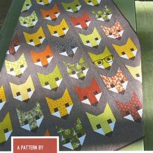 May include: A quilt pattern featuring a design of foxes with different colored fabrics. The pattern is called "Fancy Fox" and is by Elizabeth Hartman. The pattern is for a baby, lap, or twin quilt.