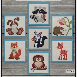 May include: A collection of seven woodland critter appliqués, including a raccoon, bunny, skunk, fox, owl, hedgehog, and deer. The appliqués are designed to decorate a 12-inch storage cube. The text "The Whole Country Caboodle" and "Caboodle Critter Storage Cubes" are also visible.