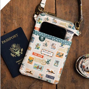 May include: A small crossbody or wristlet bag with a zipper closure. The bag is made of fabric with a vintage postage stamp pattern in shades of blue, green, and orange. The bag has a brown strap and a gold-colored metal clasp.