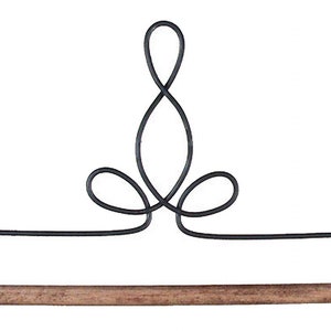 May include: A decorative paper towel holder with a black metal frame and a natural wood dowel. The metalwork features an elegant, looping design at the top. The holder is designed to be mounted on a wall.
