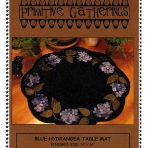 May include: Blue hydrangea table mat pattern with a black background and a wreath of blue hydrangea flowers and green leaves. Finished size: 14 inches by 16 inches. Designed by Julie Feidt.