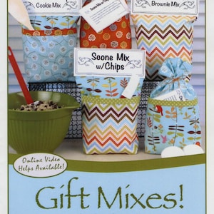 May include: Image of gift mixes, including Chocolate Chip Cookie Mix, Double Chocolate Brownie Mix, and Scone Mix with Chips. The mixes are packaged in decorative bags with labels. A green bowl and a wooden spoon are also visible. The text "Gift Mixes!" is displayed.