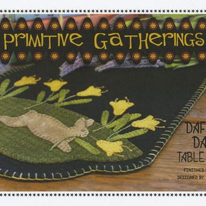 May include: A black felt table runner with a green and brown applique of a rabbit and daffodils. The text "Daffodil Dance Table Runner" is printed on the runner. The finished size is 8 inches by 26 inches.