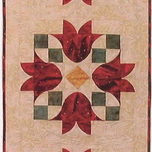 May include: A rectangular quilted table runner featuring a repeating pattern of red tulip-like shapes, green and white checkered squares, and diamond-shaped accents. The background is a light beige with a subtle floral design. The runner has a scalloped edge.