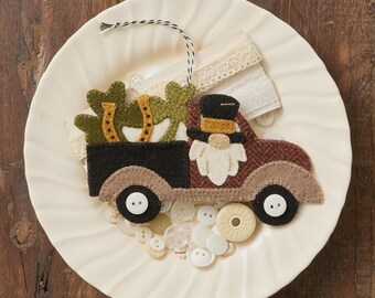 May include: A felt truck decoration with a gnome driver and shamrocks in the bed. The truck is brown, black, and tan, with white button wheels. The decoration is on a white plate. Text reads "Truckin' With My Gnomies".