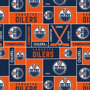 May include: A repeating pattern featuring the Edmonton Oilers logo and team name in orange, navy blue, and white. The design includes the Oilers logo, the team name, and crossed hockey sticks. The pattern is a mix of squares and rectangles.