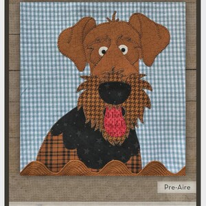 May include: Airedale appliqué design from "The Whole Country Caboodle." The design features a brown dog with a black and orange patterned body, a black nose, and a red tongue. The background is a blue and white checkered pattern. Includes precut fused appliqué for an 8" block.