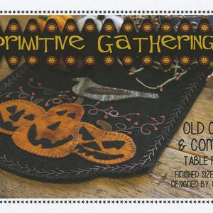 May include: A black felt table runner with an embroidered design of pumpkins and a crow. The text "Old Crow & Company Table Runner" is printed on the image. The finished size is 10 1/2 inches by 30 inches.