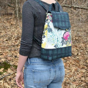 May include: A convertible backpack with a floral print and a plaid flap. The backpack converts into a cross-body bag and has an interior zip pocket and slip pockets. It measures 12-1/2 inches high, 9-1/2 inches wide, and 4 inches deep.