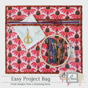 May include: A quilted project bag featuring a pink and orange coneflower pattern with a clear vinyl front pocket, a purple zipper, gold embroidery scissors, a wooden embroidery hoop with assorted embroidery floss, and a needle pack.