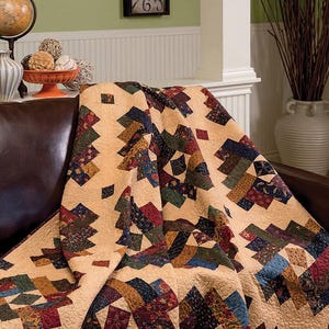 May include: A quilt pattern called "French Twist" by Doug Leko Antler Quilt Design. The quilt is made with a variety of fabrics in shades of brown, red, green, and blue. The quilt is 68 inches by 85 inches.