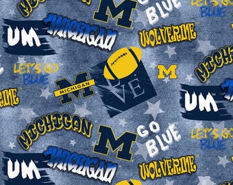 May include: A blue and yellow fabric pattern with the words "Michigan", "Go Blue", "Wolverine", "Let's Go Blue", and "UM" repeated throughout. The pattern also includes a football and a star.