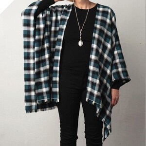 May include: A woman wearing a black shirt and jeans with a teal and white plaid fringed flannel wrap. The text "that's a wrap" and "fringed flannel wrap" is below the image.