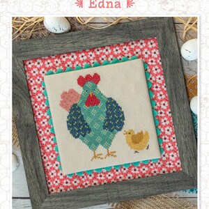 May include: Cross stitch pattern featuring a blue and green hen with a red comb and a yellow chick. The pattern is framed and has a pink and white floral background. The text "Chicken Club Edna" is at the top of the image. The text "Designed by Lori Holt Bee in my Bonnet Co." is at the bottom of the image.