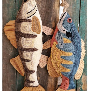 May include: Two colorful fish-shaped needlepoint wall hangings with wooden tails. The fish are a bluegill and a walleye. The text "Fish Tails Blue Gill & Walleye" is at the bottom of the image.