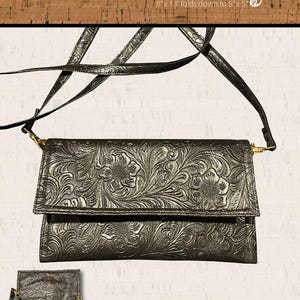 May include: A black leather crossbody bag with an embossed floral design. The bag is 8 inches by 13 inches and folds down to 8 inches by 5 inches. The pattern is by Mary Hartman for Farmer's Daughters Quilts.