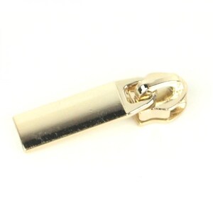 May include: Gold zipper pull with a rectangular slider. The slider is smooth and has a slightly rounded edge.
