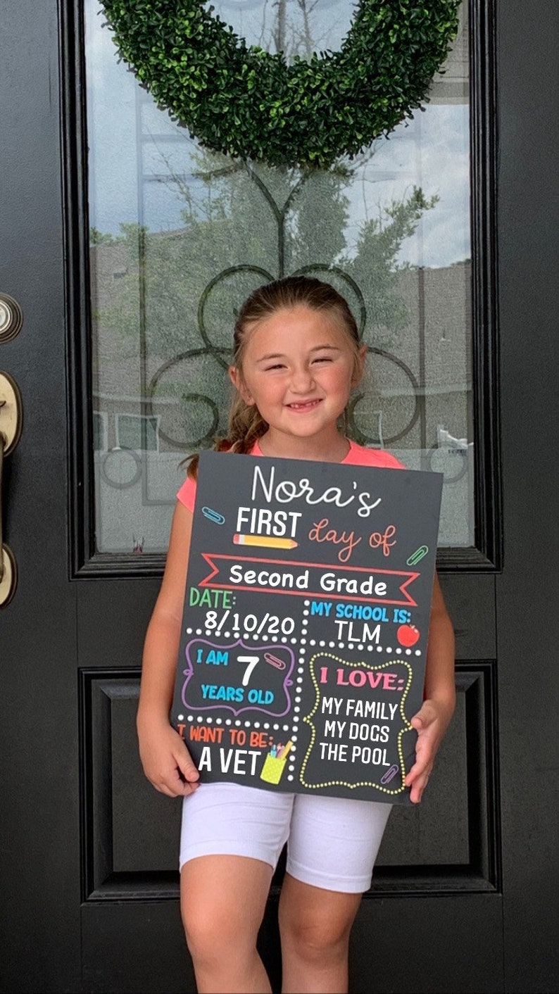 Shows child holding a milestone chalkboard sign that is reusable to document milestones for the first and last day of school.