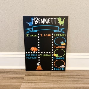 Puede incluir: Una pizarra negra con tem&aacute;tica de dinosaurios. La pizarra tiene el nombre "BENNETT" escrito en la parte superior. Tiene una lista de indicaciones para que un ni&ntilde;o las complete, como "Puedo", "Me encanta", "Me pongo de pie", "Peso", "El mejor momento", "No me gusta", "Tengo" y "Dientes".