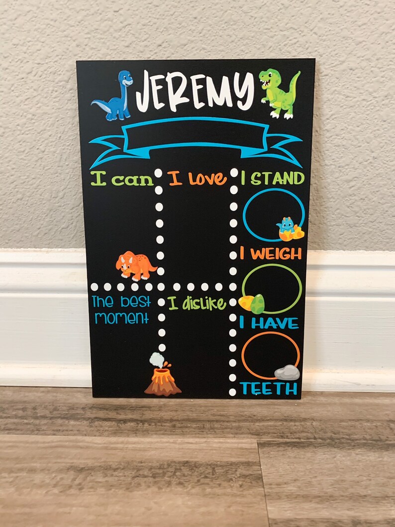 Puede incluir: Una pizarra negra con tem&aacute;tica de dinosaurios. La pizarra tiene el nombre "JEREMY" en la parte superior. Tiene una pancarta azul con borde blanco. La pizarra tiene una lista de cosas que Jeremy puede hacer, incluyendo "Puedo", "Me encanta", "Me pongo de pie", "Peso", "El mejor momento", "No me gusta", "Tengo", y "Dientes".
