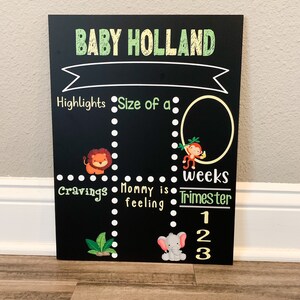 K&ouml;nnte beinhalten: Schwarze Tafel mit dem Text "BABY HOLLAND" in gelben und gr&uuml;nen Buchstaben. Die Tafel ist in vier Abschnitte unterteilt: Highlights, Gr&ouml;&szlig;e von einem, Gel&uuml;ste und Mama f&uuml;hlt sich. Jeder Abschnitt hat eine gepunktete Linie und eine entsprechende Tierillustration. Der untere Abschnitt hat den Text "Wochen" und "Trimester" mit den Zahlen 1, 2 und 3.