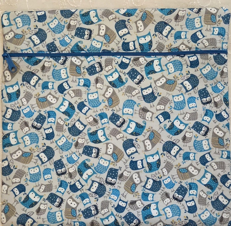 May include: A rectangular, zippered pouch featuring a repeating pattern of owls in shades of blue, gray, and white. The owls have various designs and expressions. The zipper is a contrasting blue.